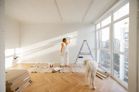 Jeune femme qui rénove en peinture son appartement avec son chien